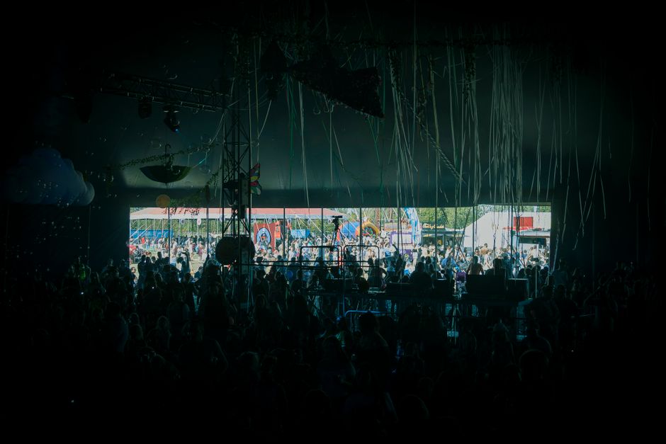 A crowd enjoying live music at a colorful outdoor festival stage.