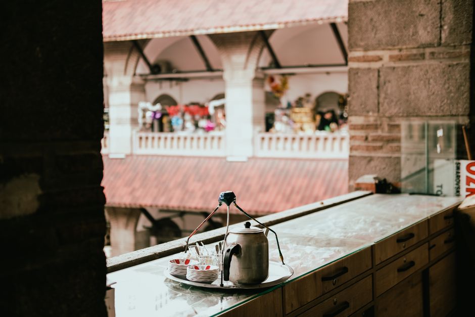 A cozy scene featuring a traditional market viewed from a counter with a tea kettle and cups.